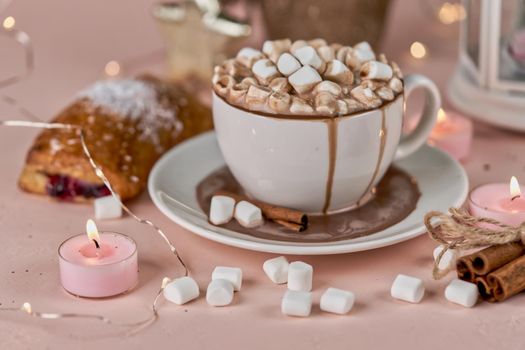 A white mug with smudges of spilled cocoa with marshmallows and burning candles on the table. Romantic sweet dinner