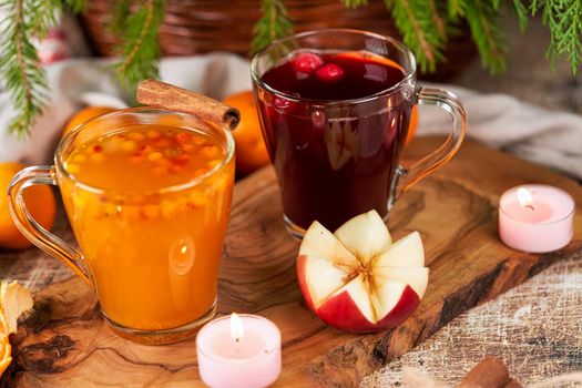 Red and yellow mulled wine in glass mugs on a Christmas table with candles. New Year still life