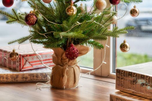 Fragment of a Christmas tree with toys and boxes with gifts on the windowsill overlooking the street