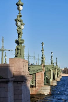 Fragment of the Trinity Bridge with ancient lanterns across the Neva River. Russia, Saint Petersburg cityscape, vertical shot