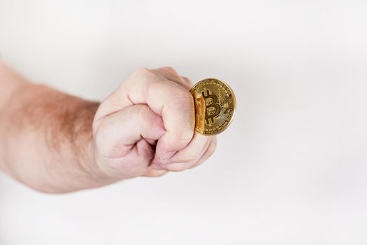 Bitcoin in the form of a round coin in a man hand in the form of a fig