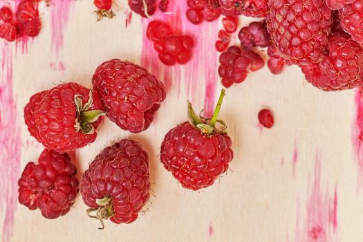 Berries of red ripe raspberries on the background of containers with juice stains from berries. Top view close up