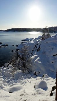 The sun shines on a snowy bay on a winter morning in Scandinavia