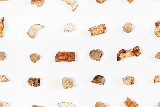 Seamless pattern from pieces of dried mushrooms scattered by lines on a light background. View from above