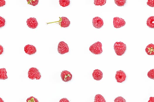 A pattern of ripe red raspberries laid out in lines on a white background in various poses. View from above