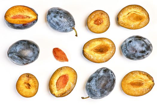 Whole and cut dark plums in various forms. Prunes lie on a light background, top view