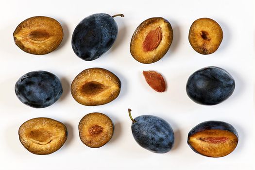 Ripe dark plums in various forms. Prunes on a light background, top view