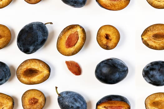 Pattern of plum berries laid out in lines on a white background in various forms. Top view, close up