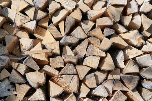 A fragment of folded chopped firewood in a woodpile. Background and texture