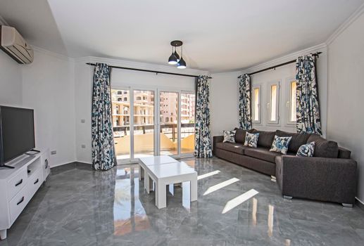 Living room lounge area in luxury apartment show home showing interior design decor furnishing with balcony