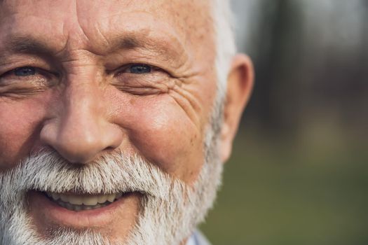 Close up portrait of happy senior man. Elderly man is smiling and looking at camera.
