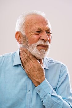 Portrait of senior man who is having pain in neck glands.