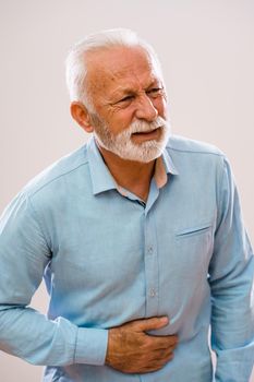 Portrait of senior man who is having pain in stomach.