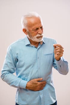 Portrait of senior man who is having pain in stomach.