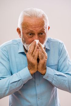 Portrait of senior man who is blowing nose.