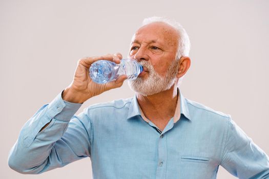 Portrait of senior man who is drinking water.