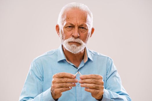 Portrait of serious senior man who is decided to quit smoking.