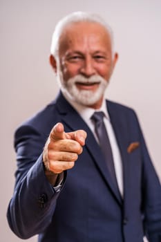 Portrait of happy senior businessman who is pointing at you.