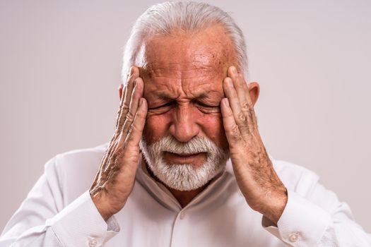 Portrait of senior man who is having headache.