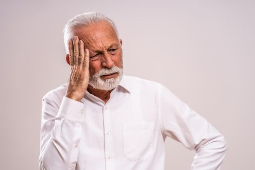 Portrait of senior man who is having headache.