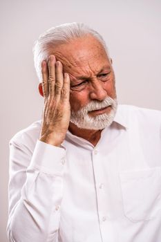 Portrait of senior man who is having headache.