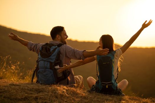 Young happy couple is hiking in mountain and looking at sunset.