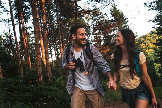 Happy couple is hiking in forest in summertime.