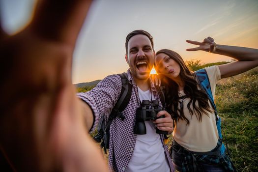 Happy couple is hiking. They are having fun with wide angle lens on camera.