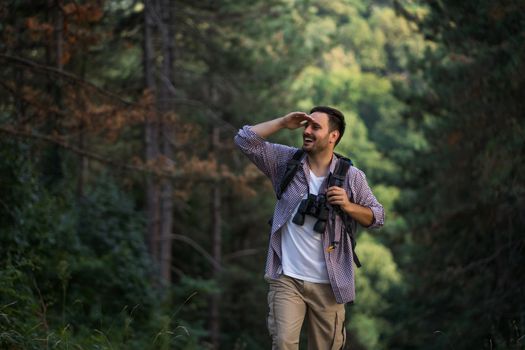 Happy adult man is hiking in forest.