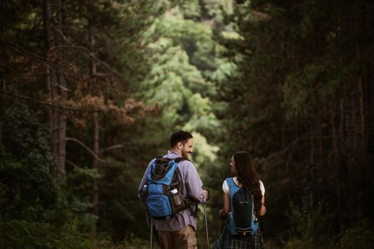 Happy couple is hiking in forest.