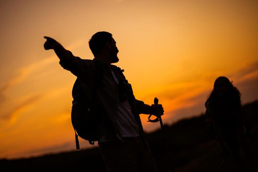 Happy couple is hiking in mountain in sunset.