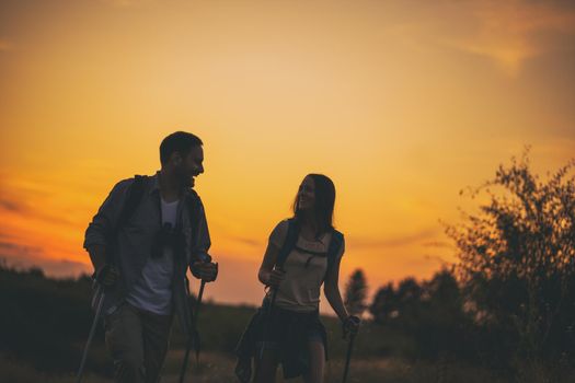 Young couple is hiking in mountain in sunset.