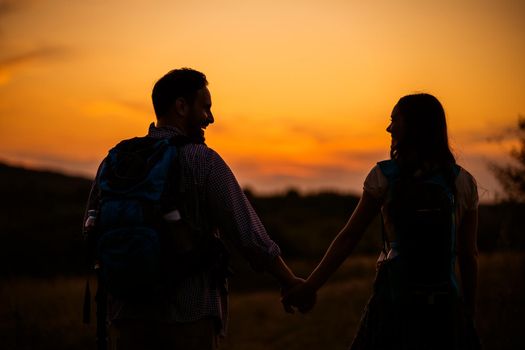 Happy couple is hiking in mountain in sunset.