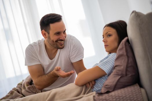 Young couple is taking in bed. Woman is offended and angry.