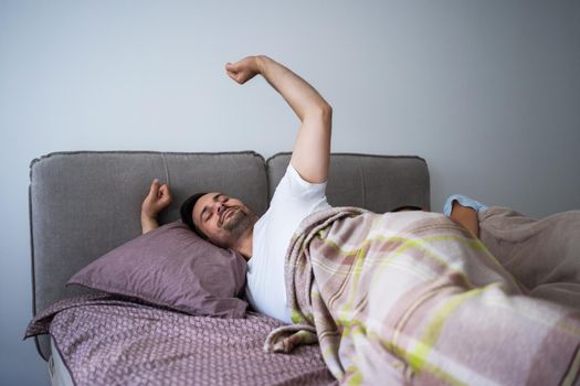 Young couple is sleeping in bed. Man is waking up for work.