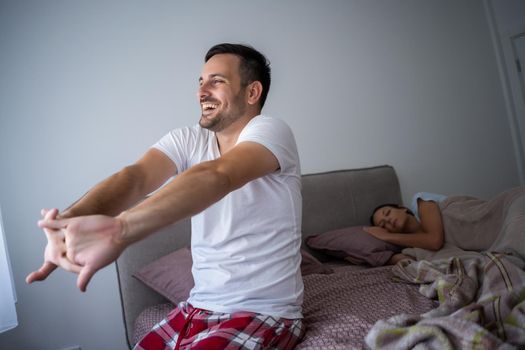 Young couple is sleeping in bed. Man is waking up for work.