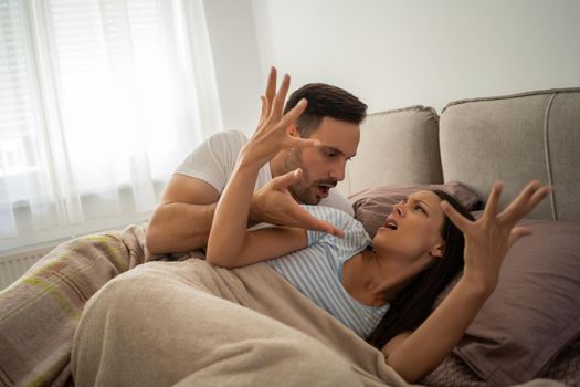 Young couple is arguing in bed in the morning.