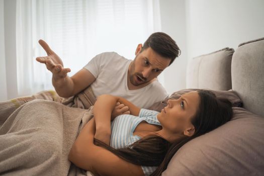 Young couple is arguing in bed in the morning.