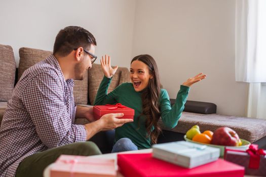 Happy couple is sharing gifts in their home.