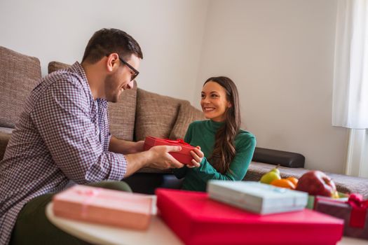 Happy couple is sharing gifts in their home.