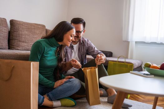 Happy couple is sharing gifts in their home.