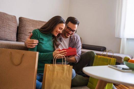 Happy couple is sharing gifts in their home.