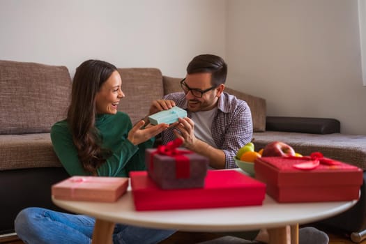 Happy couple is sharing gifts in their home.