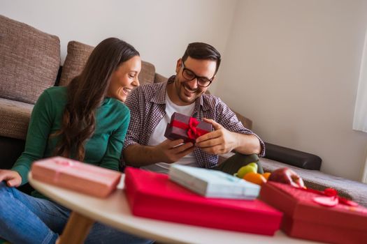 Happy couple is sharing gifts in their home.