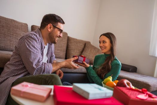 Happy couple is sharing gifts in their home.