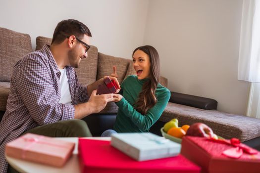 Happy couple is sharing gifts in their home.