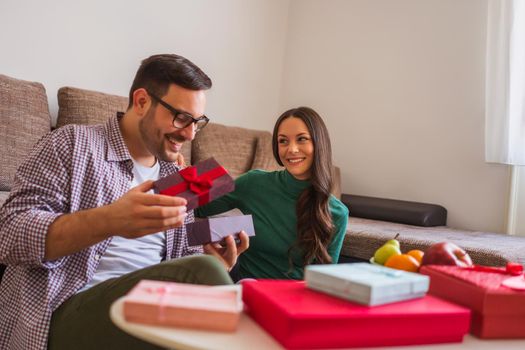 Happy couple is sharing gifts in their home.