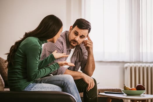 Man and woman are sitting at sofa at home and talking.