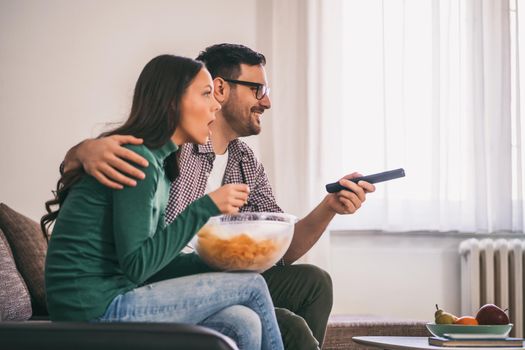 Couple is relaxing at home. They are watching tv.