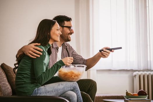 Couple is relaxing at home. They are watching tv.